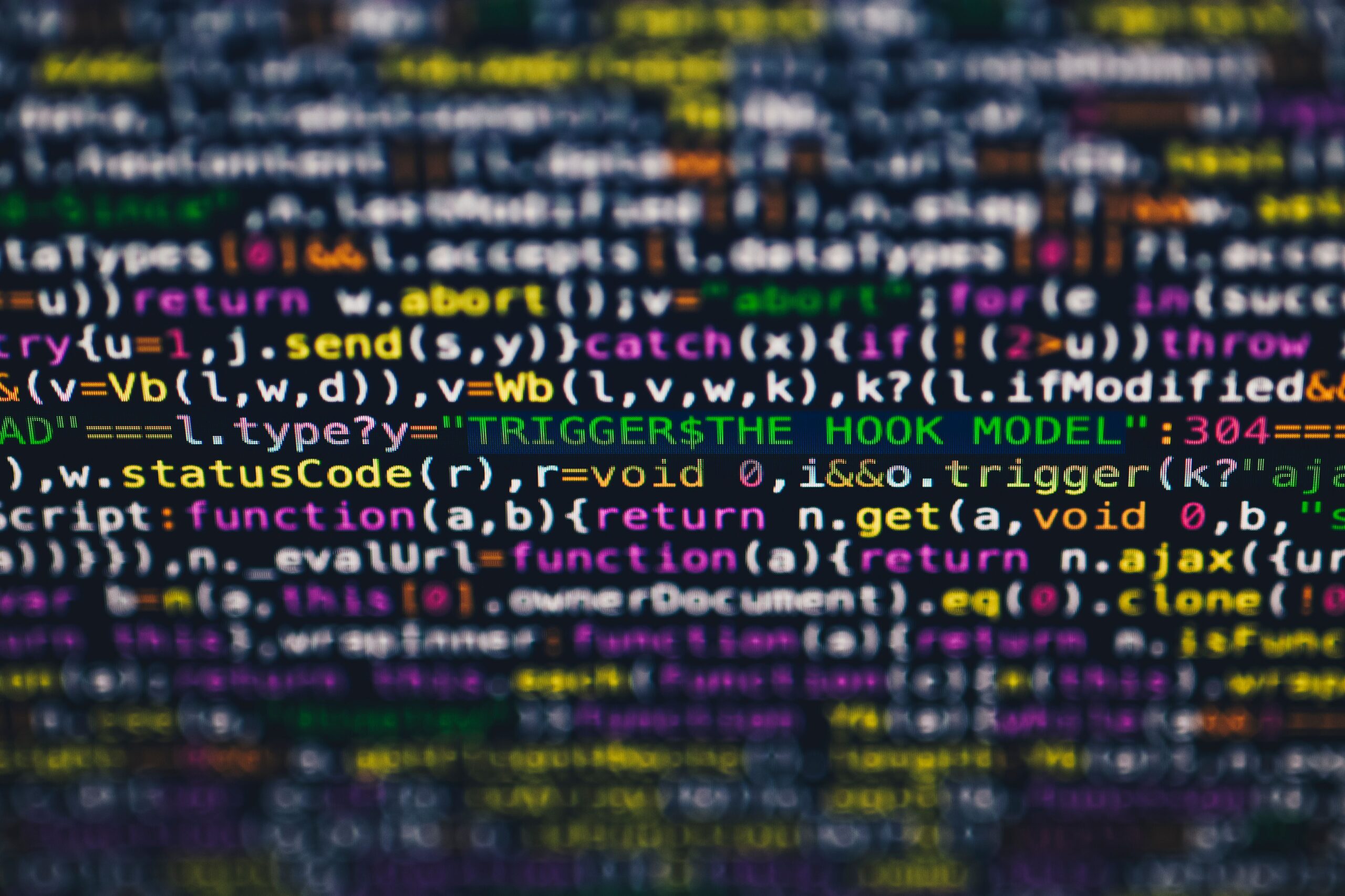 Monitor de computador exibindo linhas de código de programação coloridas, representando o processamento de dados e inteligência artificial aplicados à análise de peças e recursos jurídicos.